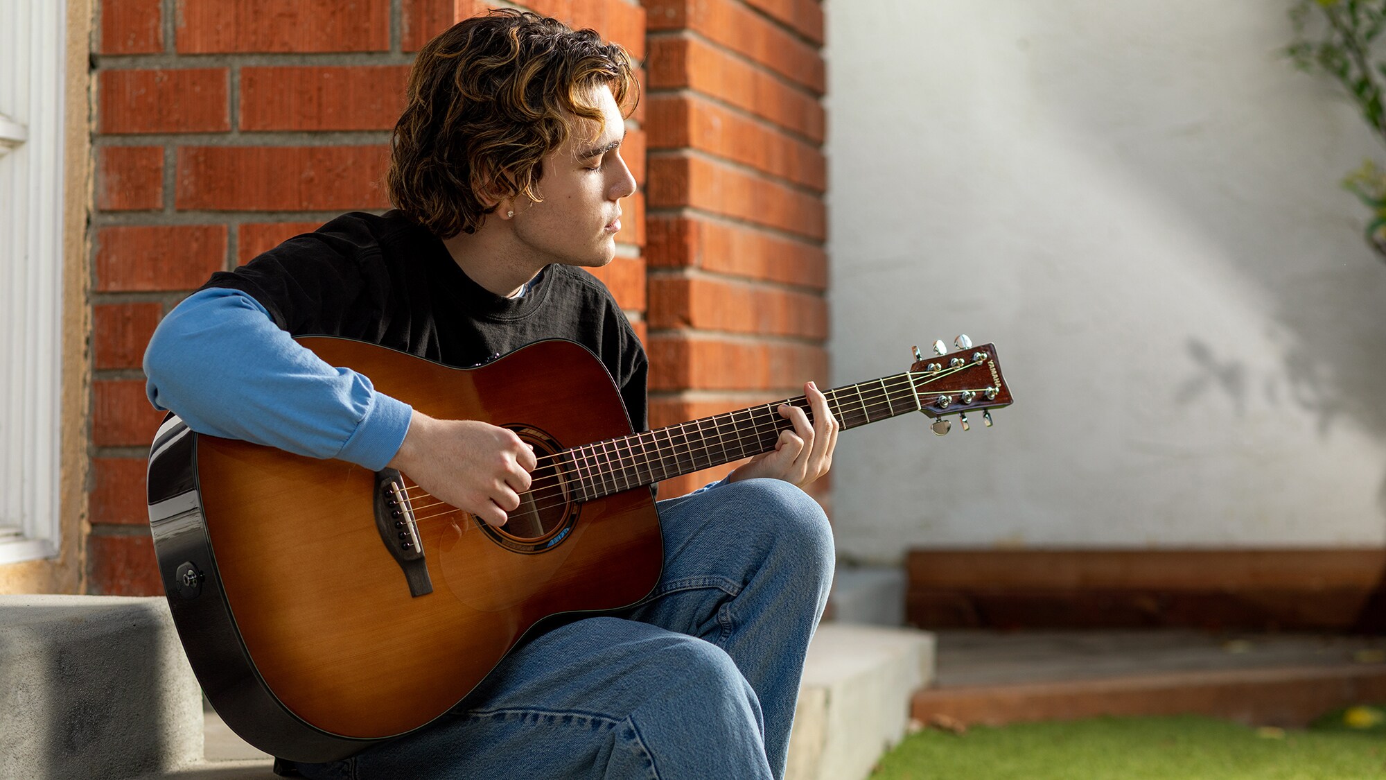 Un hombre tocando una guitarra acústica TAG1 E al aire libre