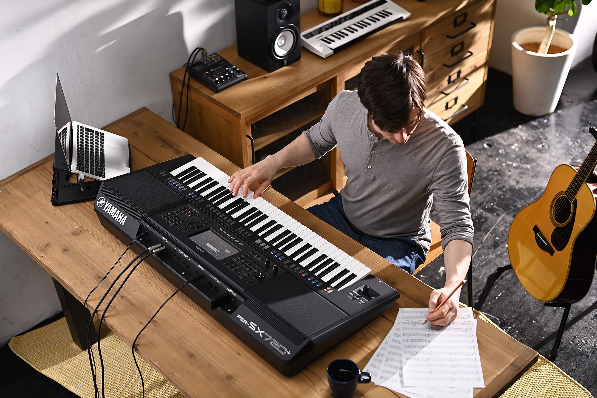 Foto de una persona escribiendo en una partitura mientras toca el Yamaha Arranger Workstation PSR‑SX720+