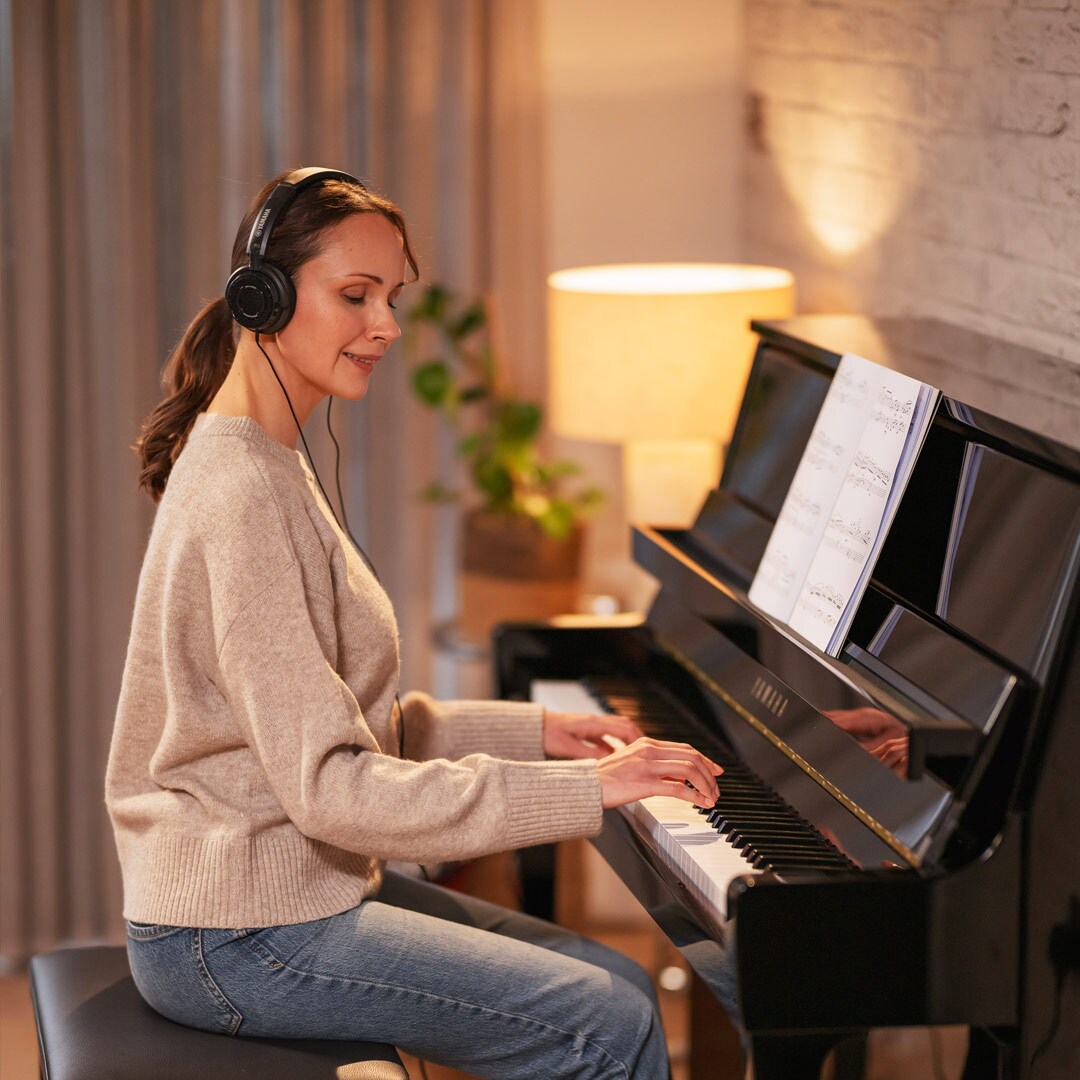 Una mujer disfruta tocando el piano con auriculares