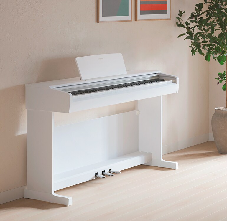 Un salón con un piano ARIUS blanco, con plantas de interior y un sofá, integrado de forma armoniosa en la decoración