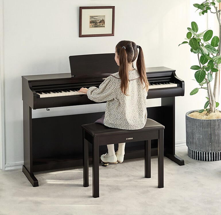 Una niña practicando con un piano ARIUS en un salón