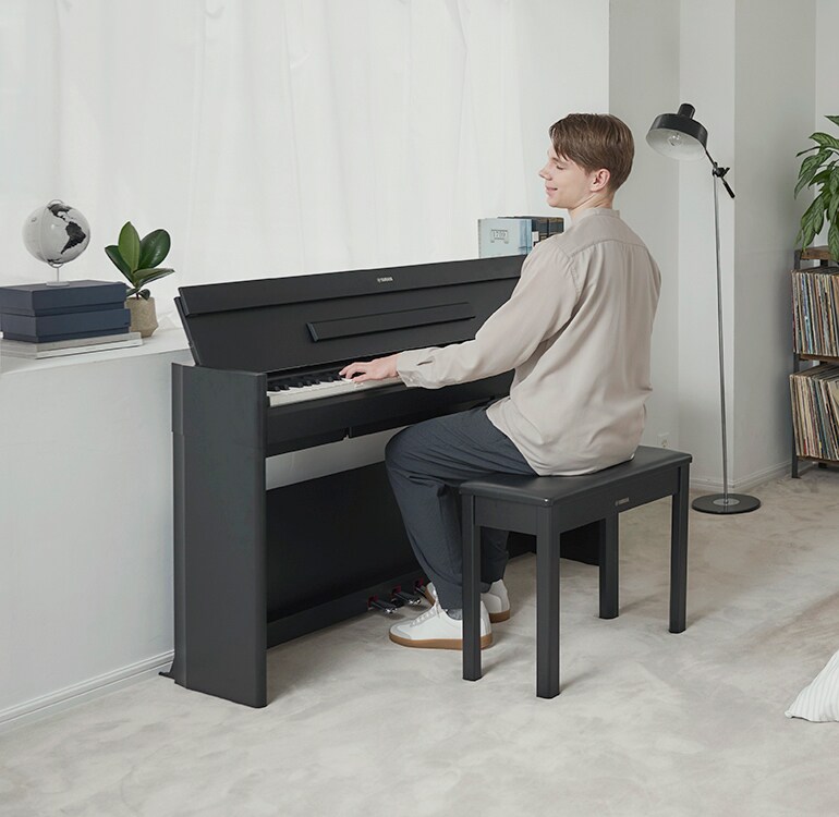 Un hombre tocando un piano ARIUS en un dormitorio en un ambiente relajado